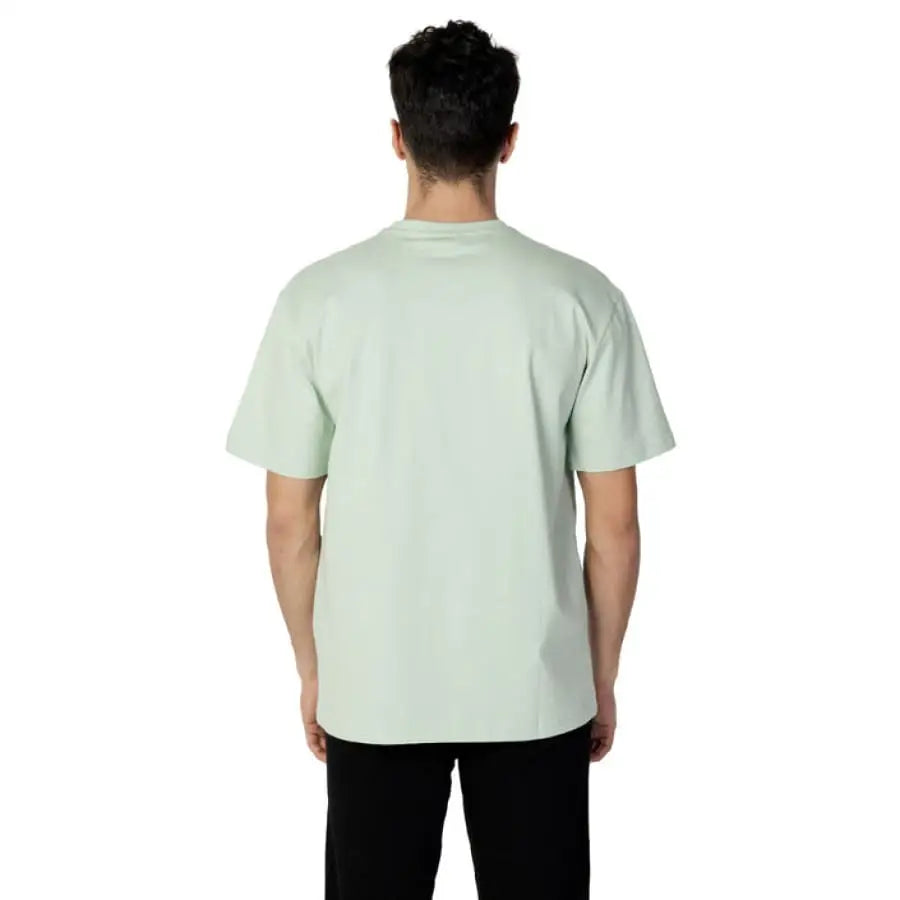 Fila Men T-Shirt model posing in green shirt and black pants by Fila Fila Men
