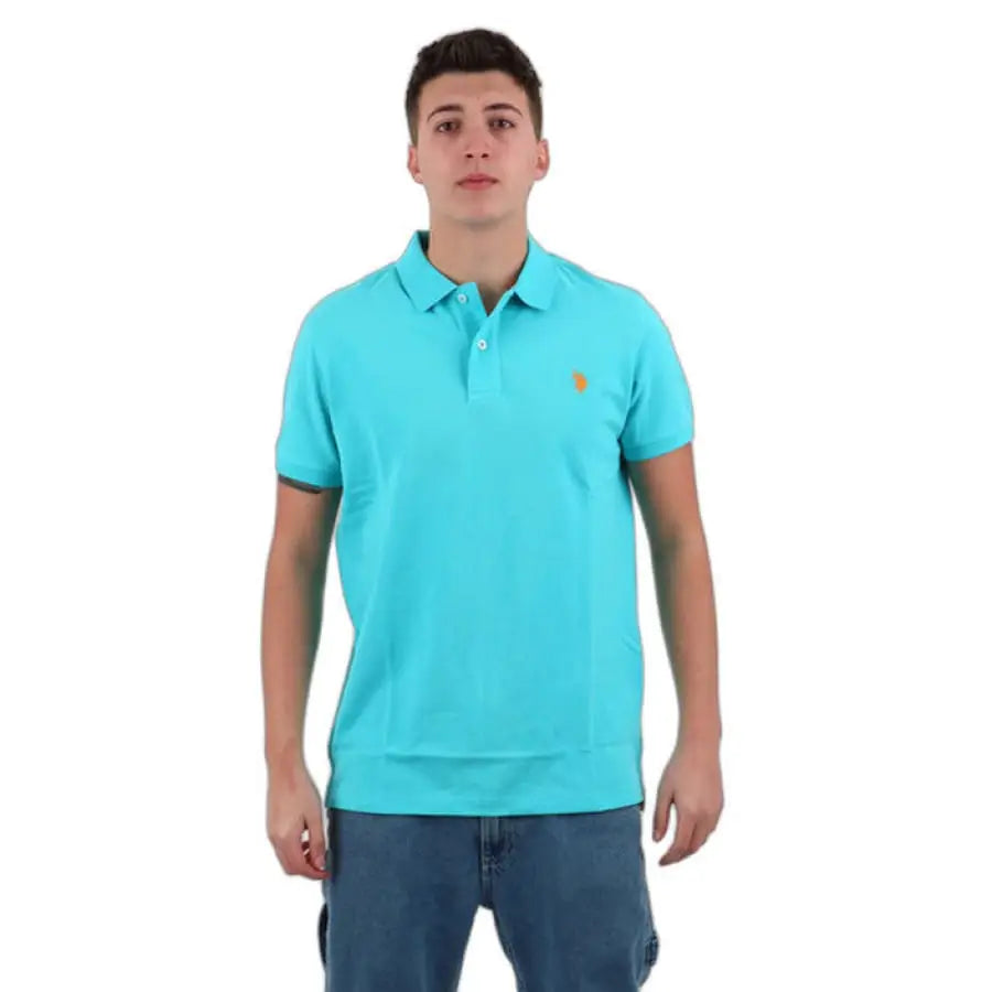 Man in turquoise U.S. Polo Assn. shirt and jeans showcasing men polo apparel accessories.